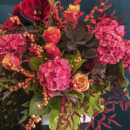 Colorful was an understatement for this flower arrangement of garden roses, hydrangeas, nandina foliage, ilex berries and red amaryllis.